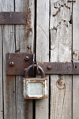 Image showing old rusty padlock on wooden door