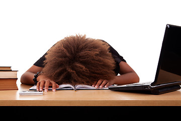 Image showing Stressed young black woman,  sitting at a table among books and laptop 