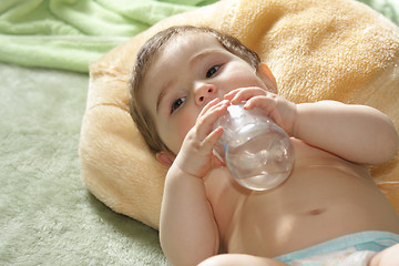 Image showing Baby with bottle laying on rug