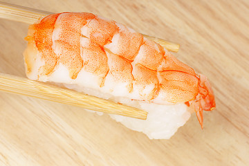 Image showing Chopsticks holding sushi