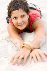 Image showing brunet woman in red lying on a sand