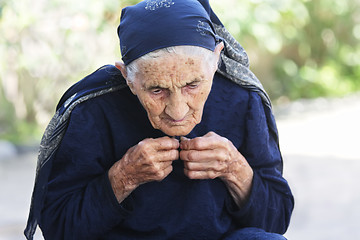 Image showing Elderly woman buttoning dress up