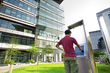 Image showing asia boy play the touch screen in modern building outside