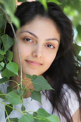 Image showing Young woman among tree leaves