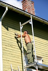 Image showing Man scraping off old paint