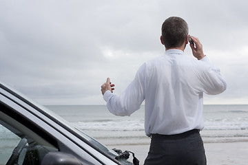 Image showing Businessman talking on cell phone at the sea