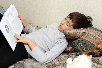 Image showing boy on bed with cat, reading bok