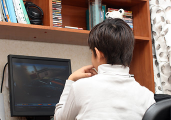 Image showing boy at table, looking to monitor