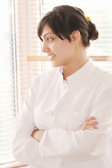 Image showing Smiling brunette in smock looking to window