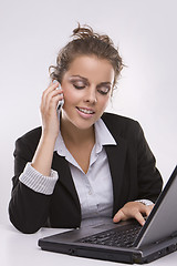 Image showing woman using a laptop computer and talking on the phone