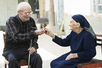 Image showing Senior man giving cherry to woman