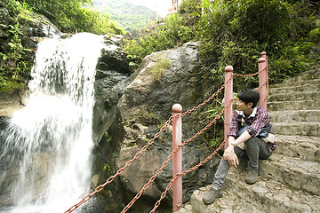 Image showing chinese man sitting on the stair in the forest and looking at th