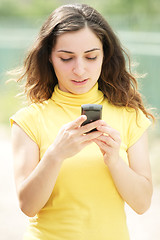 Image showing Young woman reading message on cellphone