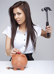 Image showing  Young woman breaking a piggy bank