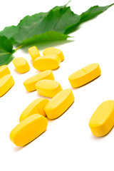 Image showing yellow vitamin pills over green leaves