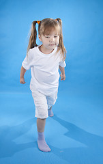 Image showing Small serious girl is posing as fighter isolated on blue