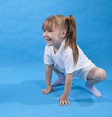 Image showing Small girl is posing as frog on blue