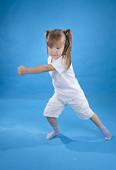 Image showing Small serious girl is posing as fighter isolated on blue