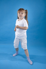Image showing Small serious girl is posing as fighter isolated on blue