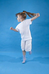 Image showing Small serious girl is jumping isolated on blue