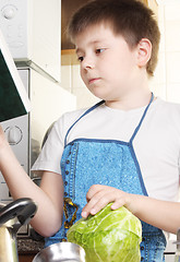 Image showing Boy with cabbage looking to cookbook