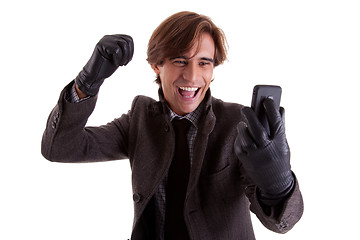 Image showing Portrait of a young happy businessman looking to the phone, in autumn/winter clothes