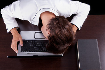 Image showing Tired young businessman with head on the computer 