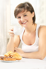 Image showing Smiling cute woman drinking tea with cakes