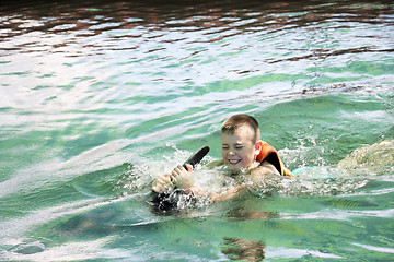 Image showing Boy swimming with dolphin