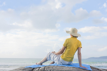 Image showing Woman sitting on a rock at the sea