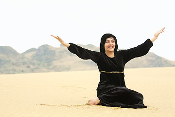 Image showing Happy woman in shawl sitting on sand