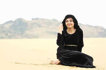 Image showing Woman in shawl sitting on sand