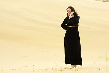 Image showing Woman walking by desert calling on cellphone
