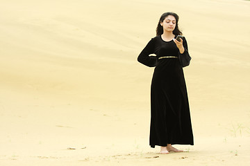 Image showing Woman in desert messaging on cellphone