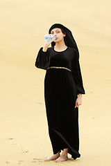Image showing Woman in desert drinking water from bottle