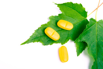 Image showing yellow vitamin pills over green leaves