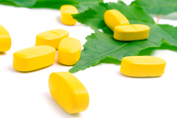 Image showing yellow vitamin pills over green leave