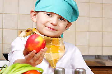 Image showing Little cook boy giving red apple