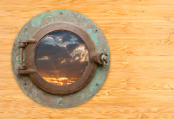 Image showing Antique Porthole with View of Sunset on Bamboo Wall