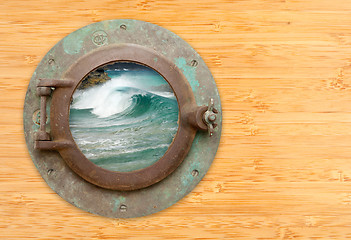 Image showing Antique Porthole with View of Crashing Waves on a Bamboo Wall Ba