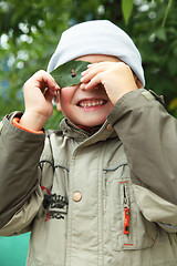 Image showing Smiling boy looking through leaf