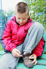 Image showing Boy clasping shoes