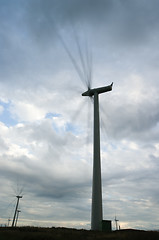 Image showing Wind turbines spinning fast on windy day