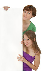Image showing Two friendly young women holding a blank banner ad