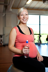 Image showing Pregnant woman relaxing while holding water bottle.