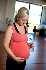 Image showing Pregnant woman relaxing while holding water bottle.