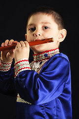 Image showing Little kid playing wooden flute