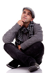 Image showing Portrait of a young man sitting on the floor, thinking and looking up