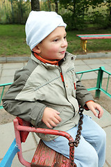 Image showing Little boy on rolling swing looking sideways