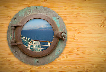 Image showing Antique Porthole on Bamboo Wall with View of Ship Deck Railing a